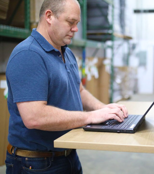 Man in warehouse working on his laptop